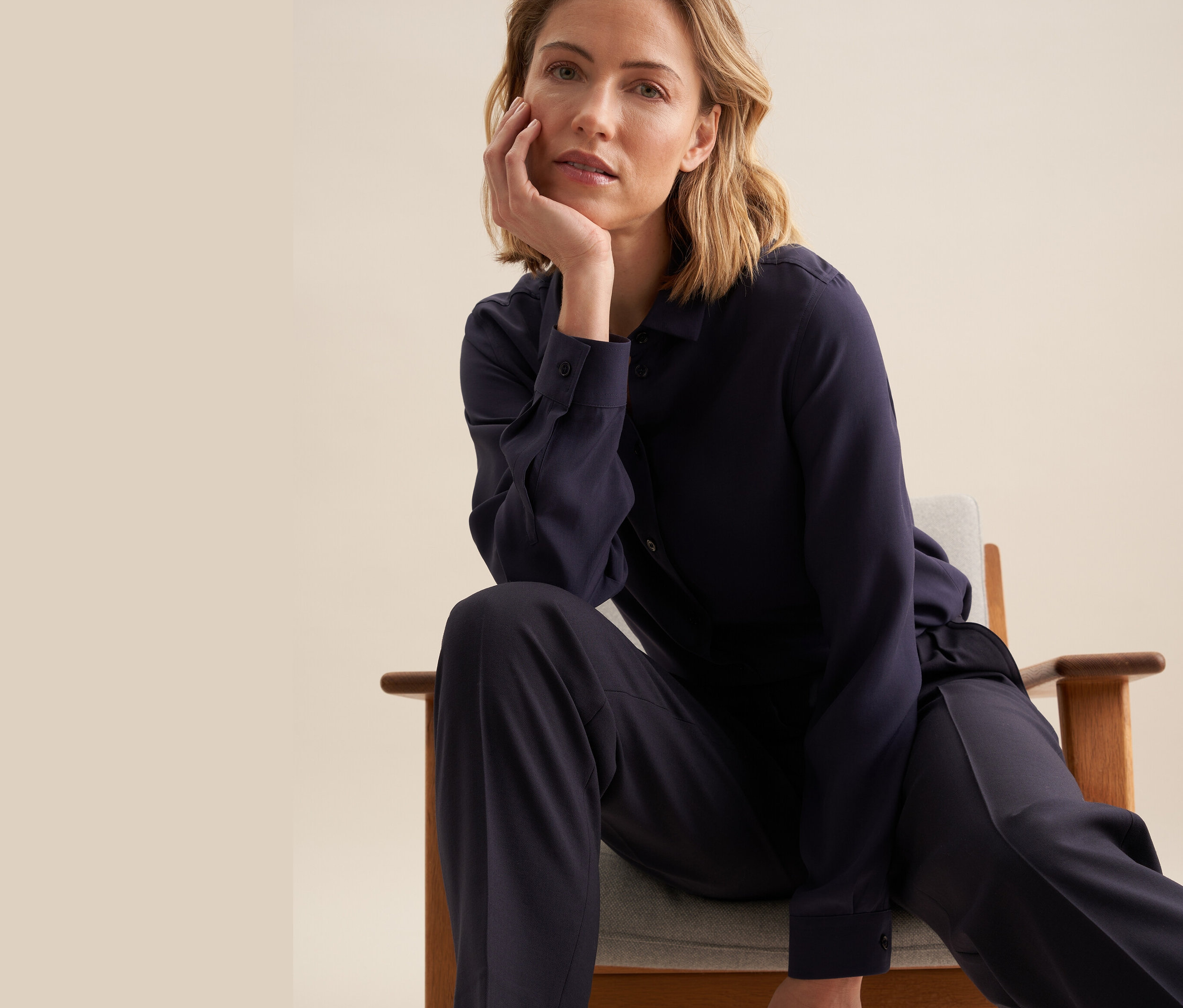 Frau sitzt auf einem Stuhl und trägt eine Seidensticker Bluse aus Viskose.