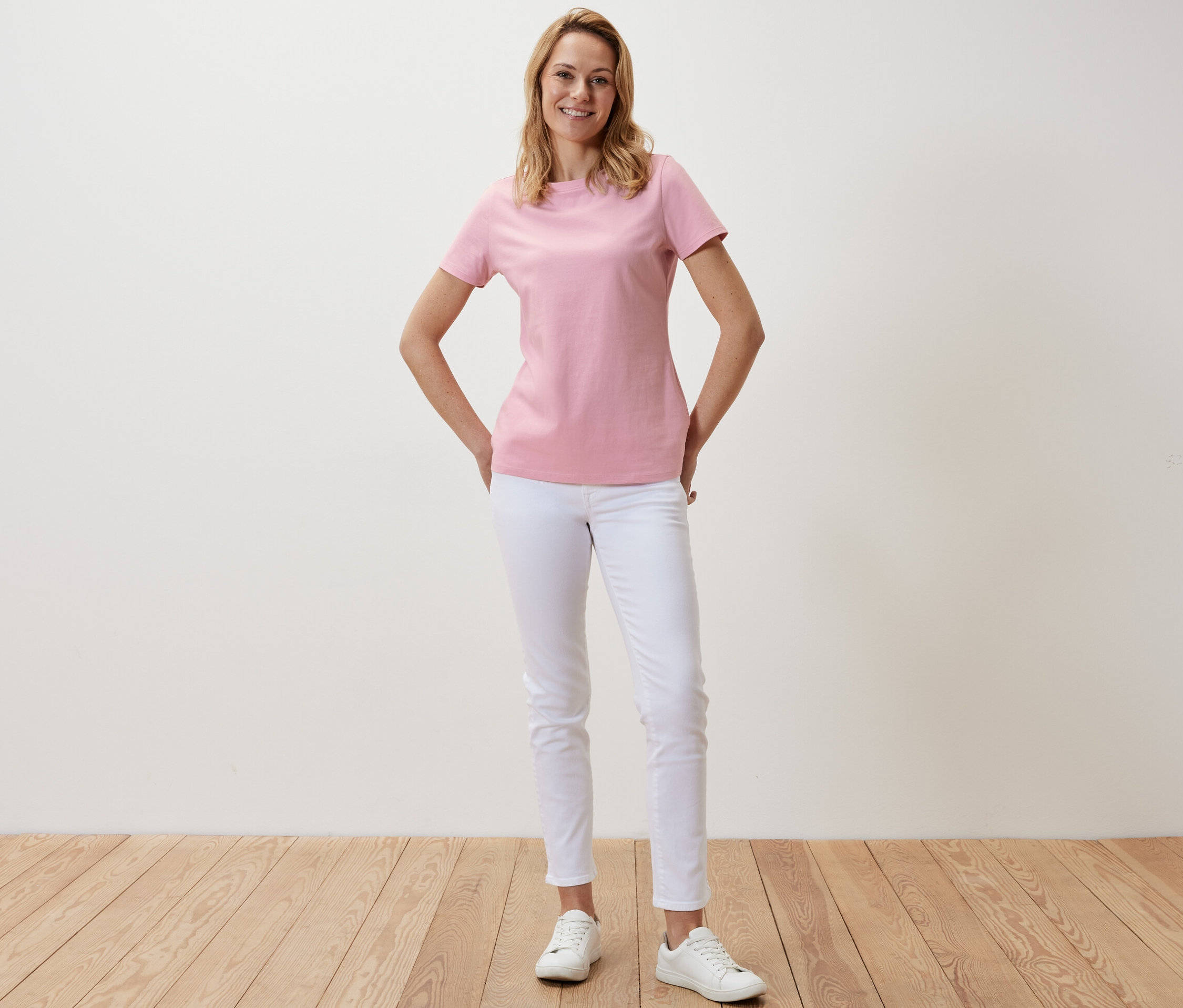 Frau posiert in einem rosafarbenen Basic T-Shirt.
