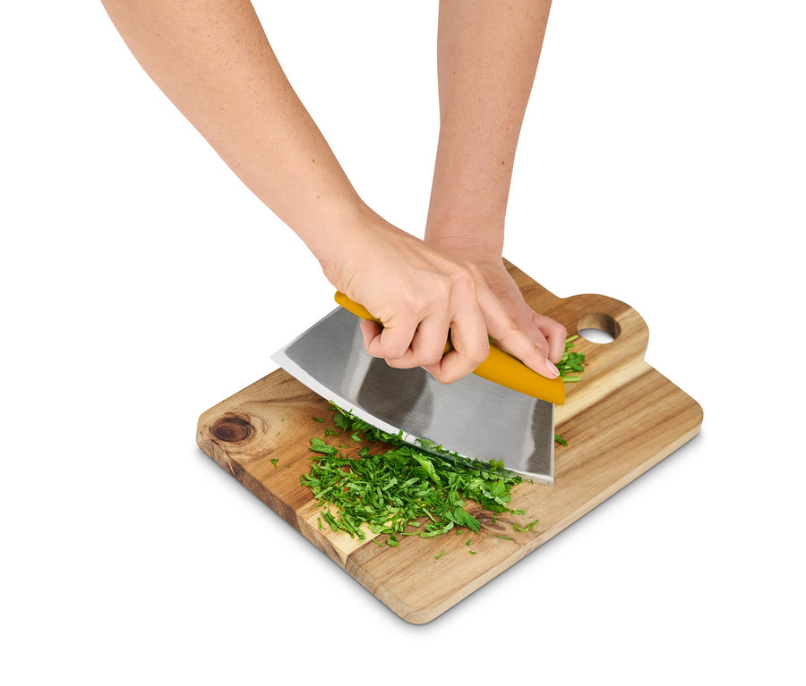 Hände hacken Kräuter mit einem Wiegemesser auf einem Holzbrett.