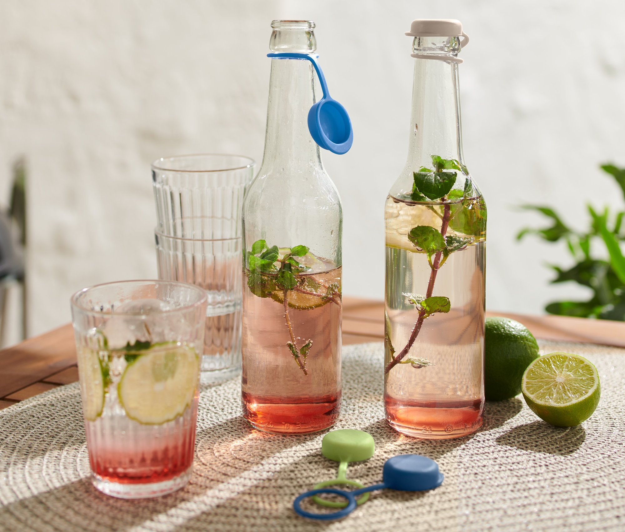 Zwei Getränkeflaschen und 4 Flaschenverschlüsse auf einem Tisch.