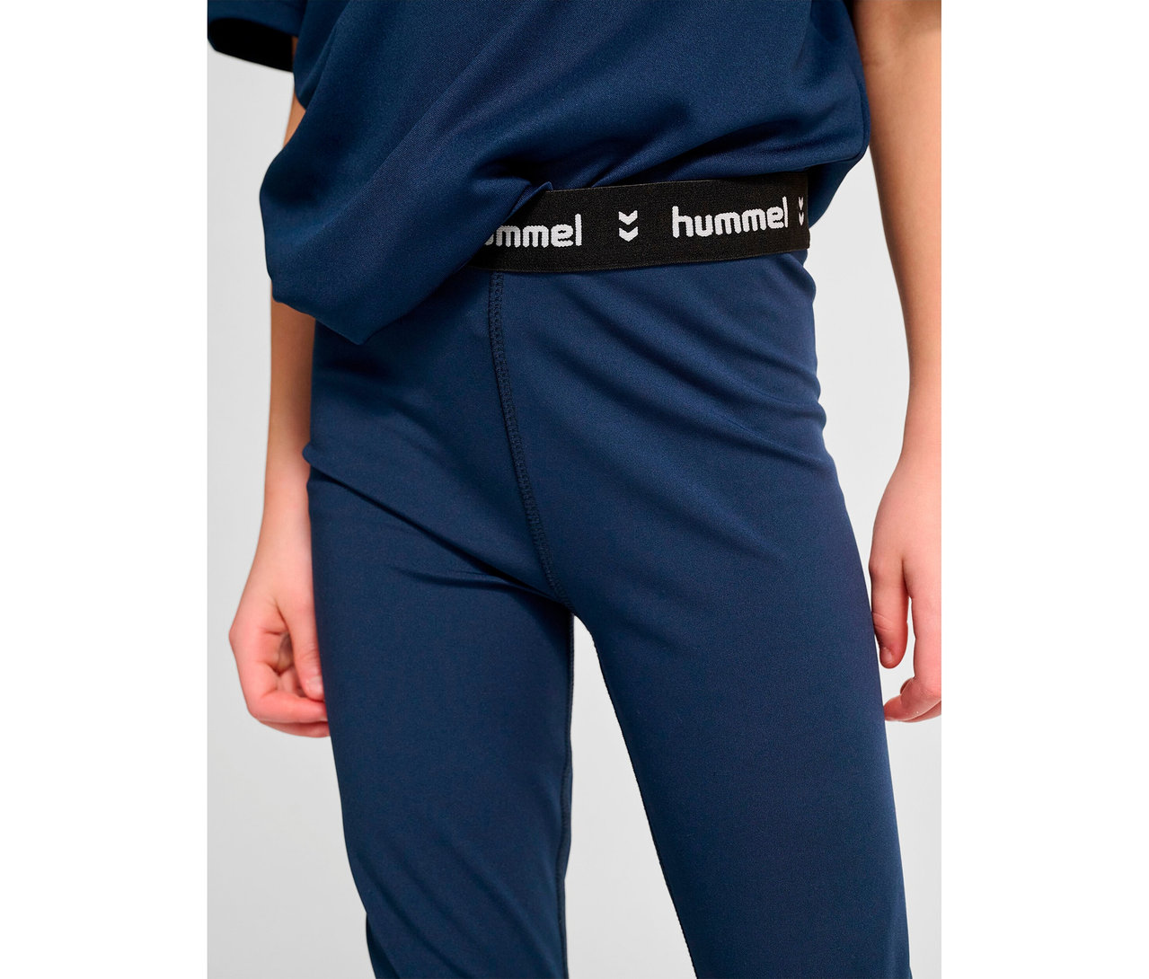 Nahaufnahme einer Person, die marineblaue HUMMEL HMLJR Pulse Mid Waist Tight trägt.
