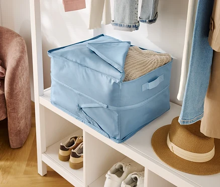 Hellblaue Stoffaufbewahrungsbox mit Deckel auf einem weißen Regal neben Schuhen und einem Hut.