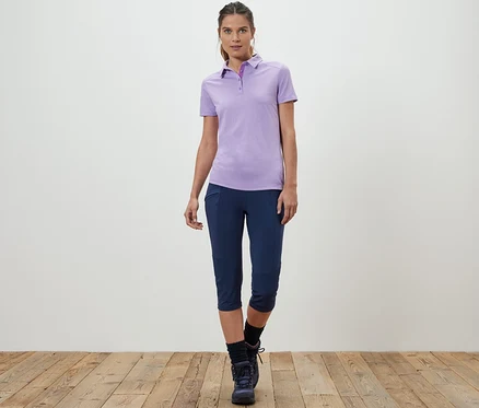 Frau posiert in lila Poloshirt und 3/4-Trekking-Tight.