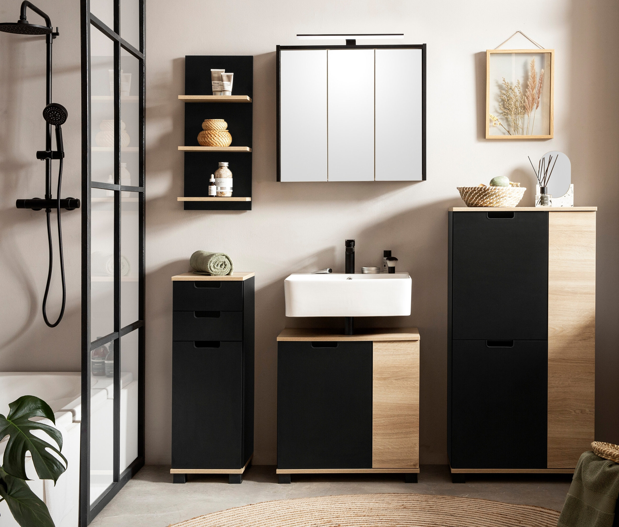 Badezimmer mit Waschbecken, Emmik Spiegelschrank, matt schwarz, Emmik Highboard schwarz/weißeiche, und Emmik Regal schwarz/weißeiche.