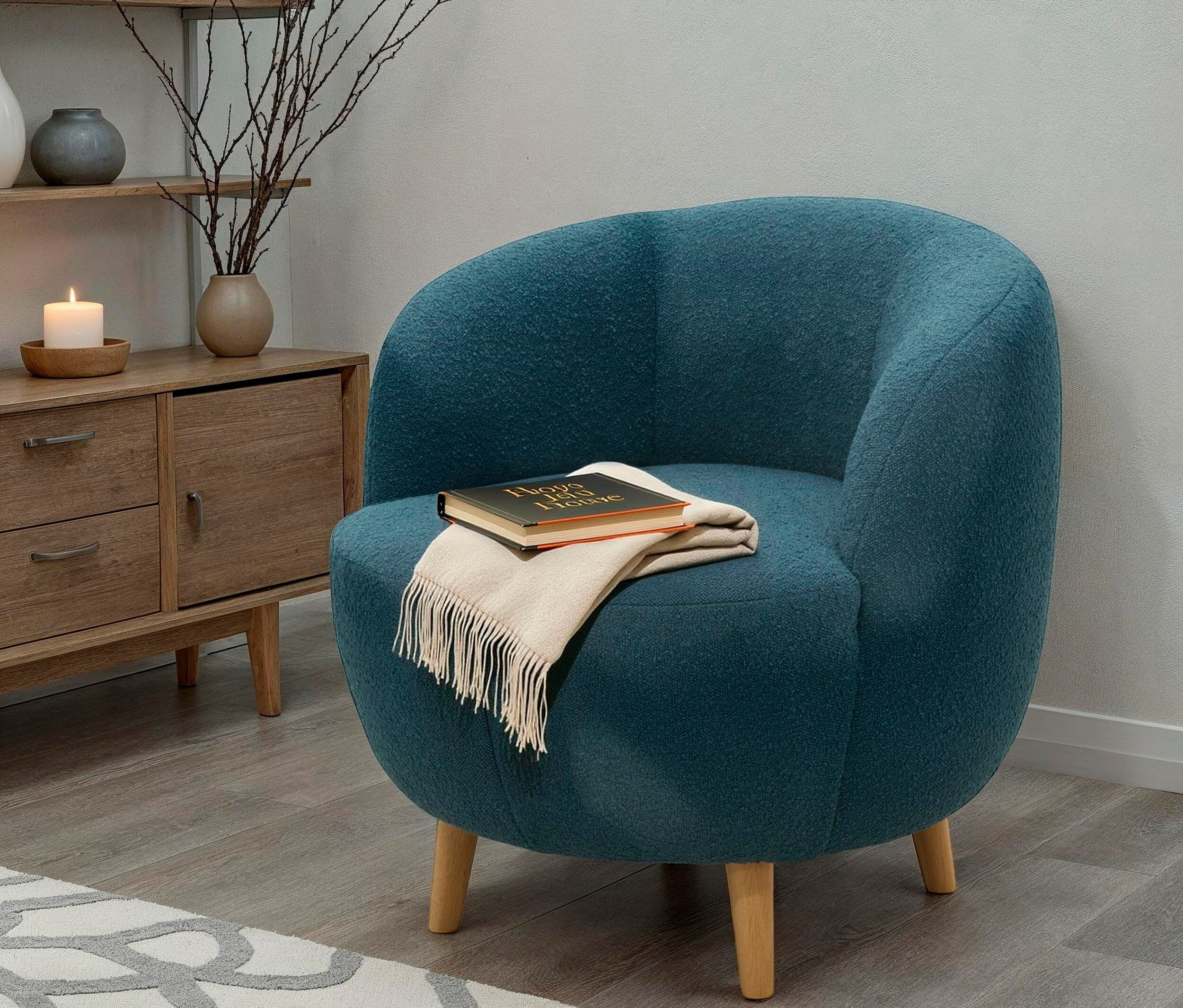 Türkisfarbener Sessel mit Buch und Überwurf im Wohnzimmer.