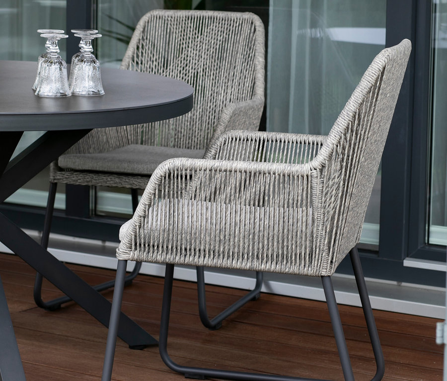 Zwei deVries 2 Dining-Sessel und ein Tisch mit zwei Gläsern auf einer Terrasse.