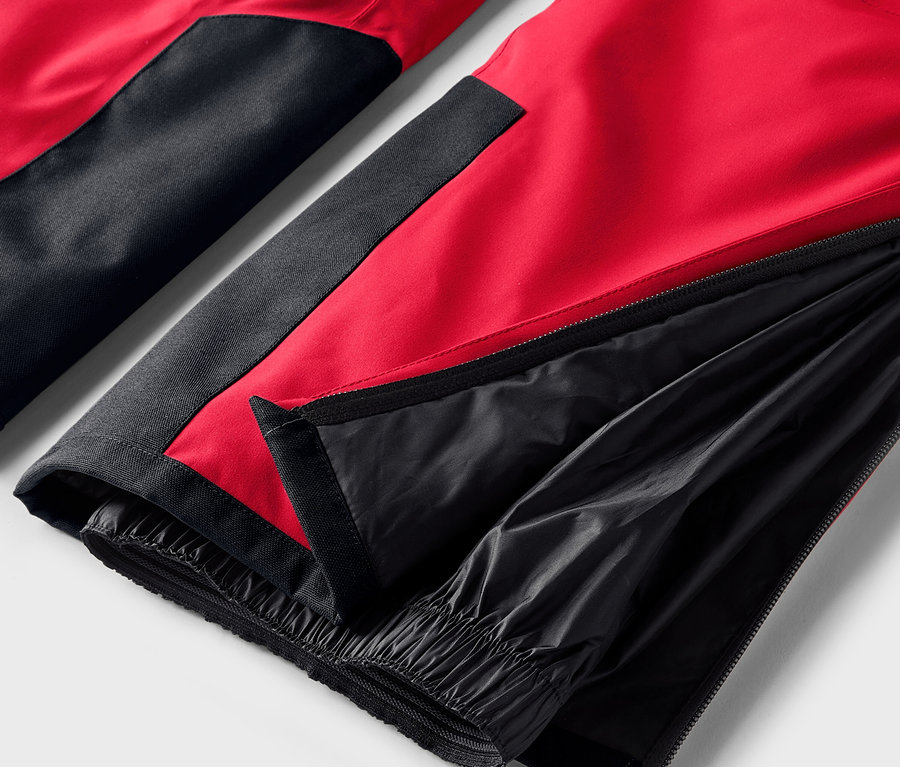 Detailaufnahme einer rot-schwarzen Hose mit geöffnetem Reißverschluss am Bein.