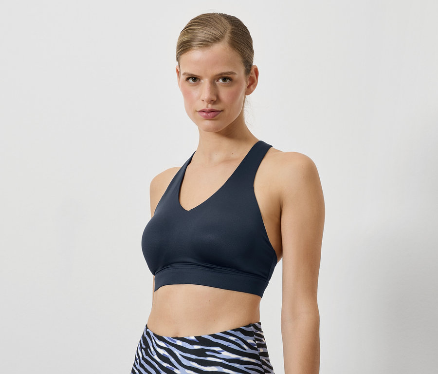Frau trägt einen dunkelblauen Sport-BH und Leggings mit Tiermuster.
