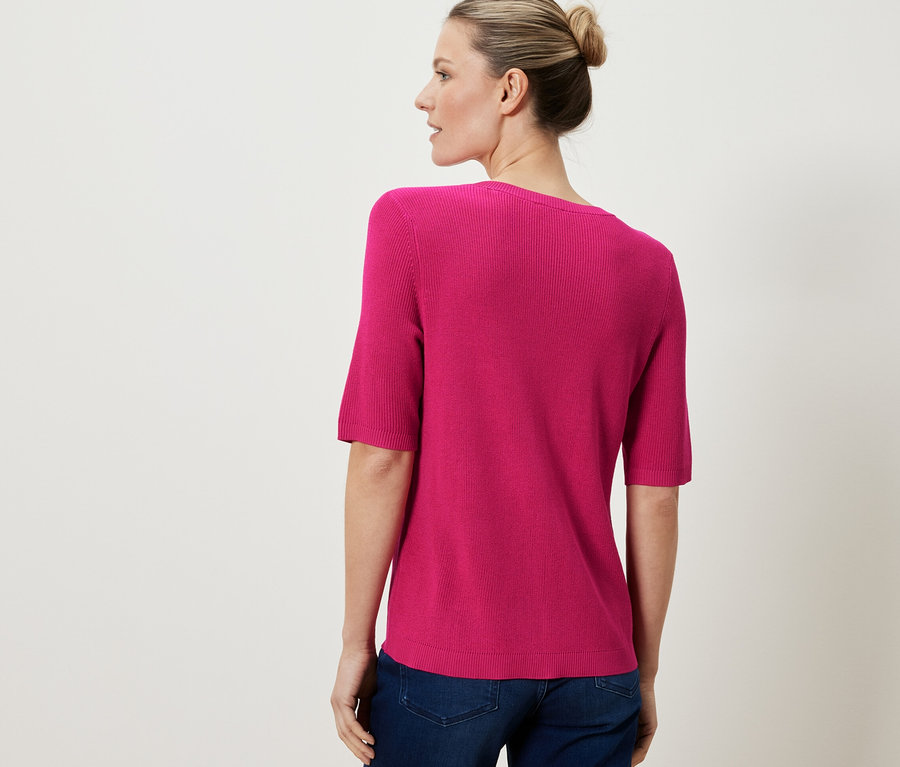 Frau trägt einen rosafarbenen Feinstrick-Cardigan mit Leinen.