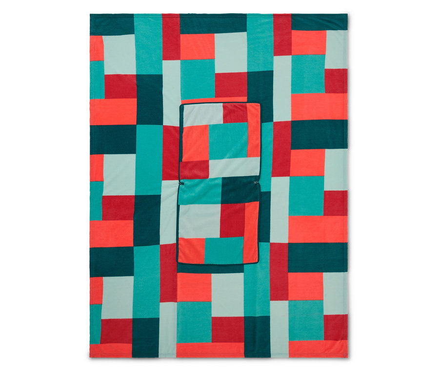 Eine Decke mit einem geometrischen Muster aus roten, türkisfarbenen, dunkelgrünen und hellblauen Blöcken, mit einer aufgenähten Tasche.