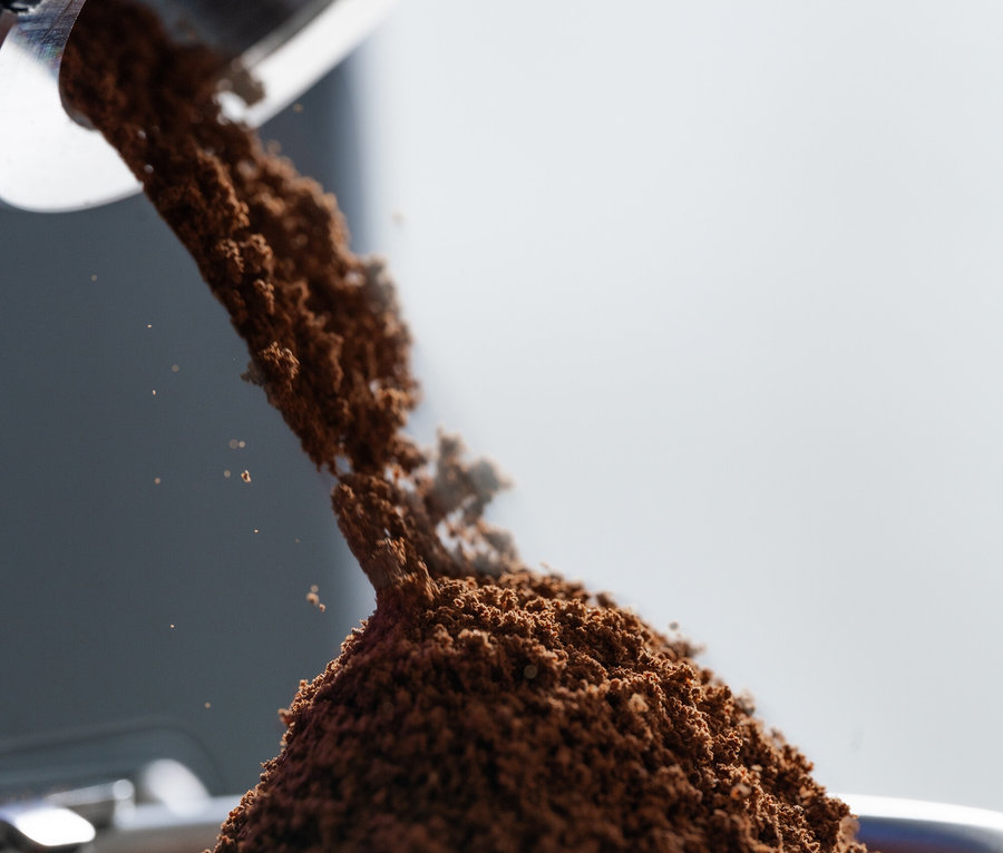 Kaffeepulver wird aus einer Mühle in einen Siebträger gefüllt.