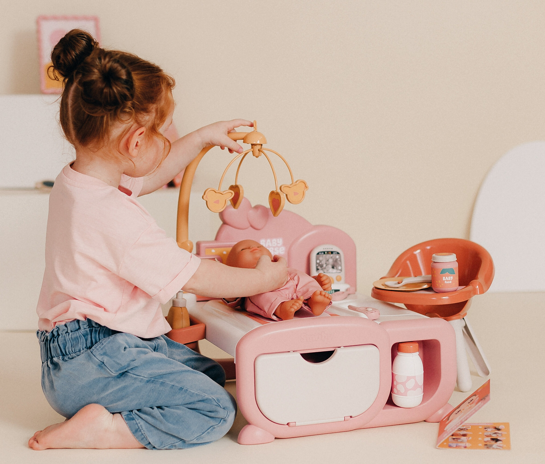 Kind spielt mit dem 3-in-1 Smoby Baby Nurse Cocoon, das eine Puppe, ein Bett und einen Hochstuhl umfasst.