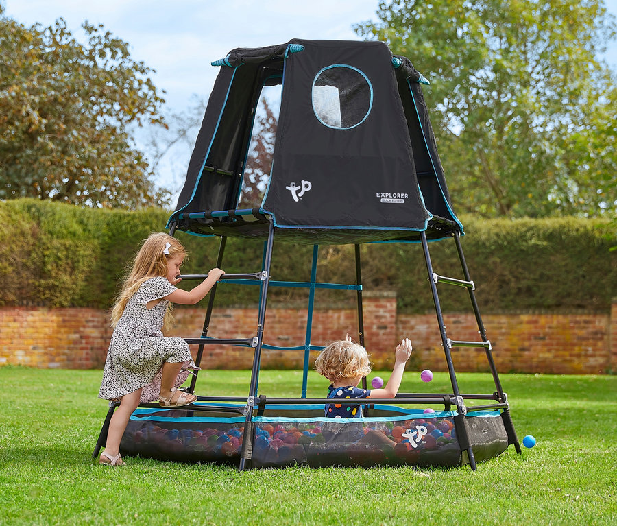 Mädchen klettert auf den Kletterturm »Explorer«, während ein Kind im Bällebad spielt.