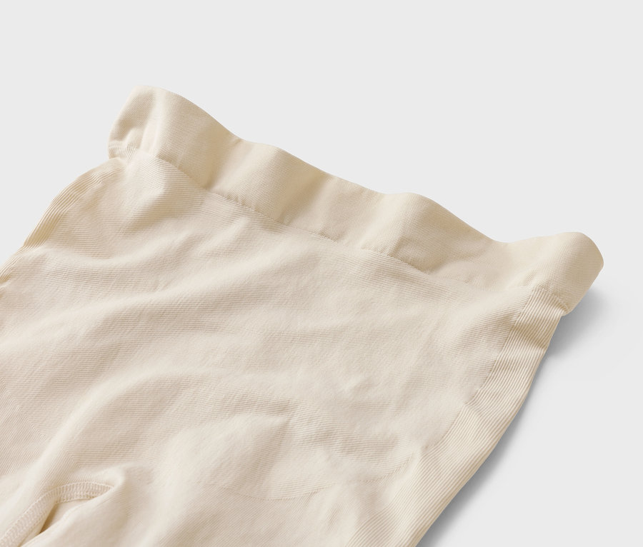 Nahaufnahme von beigen Leggings mit hohem Bund auf weißem Hintergrund.