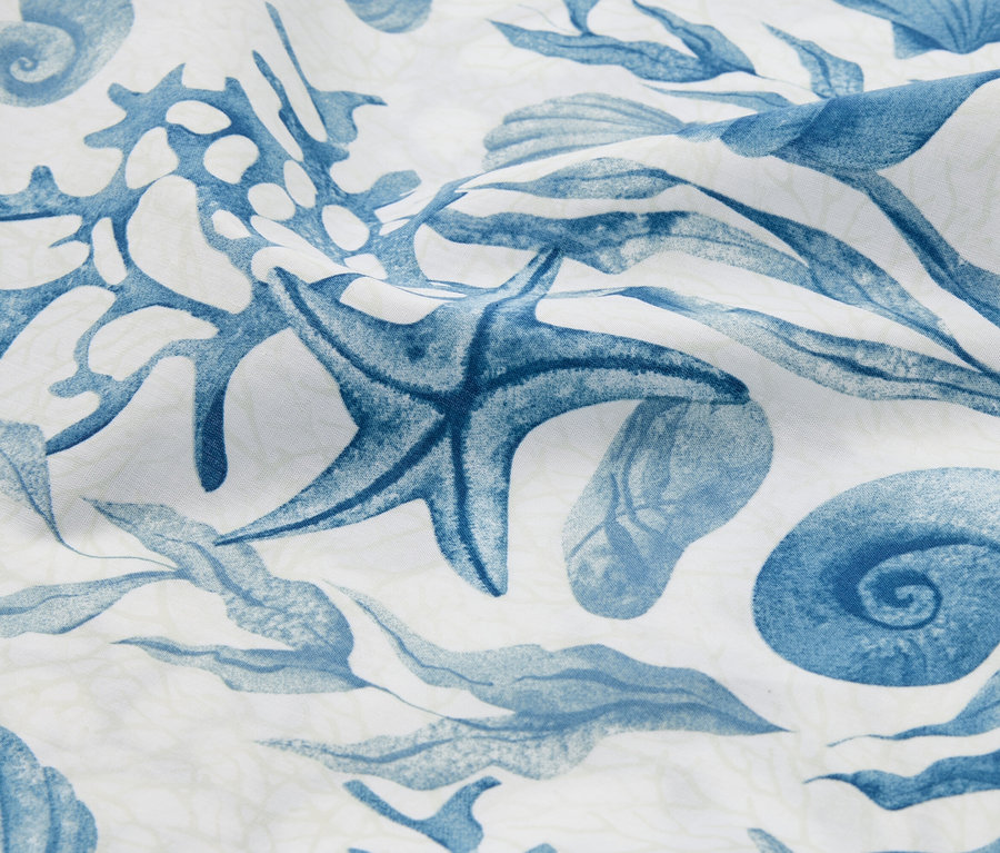 Nahaufnahme eines Stoffes mit blauem Seestern-, Muschel- und Algenmuster.