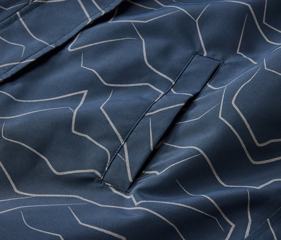 Nahaufnahme einer marineblauen Jacke mit hellgrauem Muster und einer Tasche.