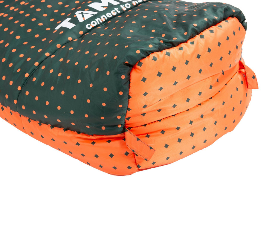 Nahaufnahme eines zusammengerollten Schlafsacks mit einem Muster aus orangefarbenen Punkten auf dunkelgrünem Stoff und schwarzen Quadraten auf orangefarbenem Stoff.