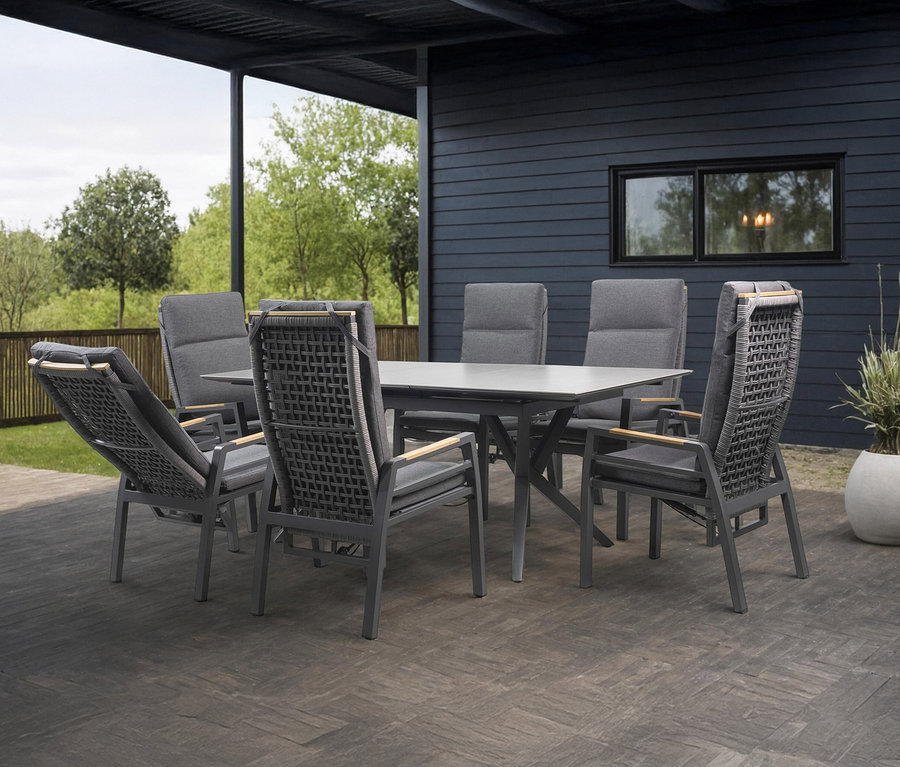 Sechs graue Stühle stehen um einen grauen Tisch auf einer Terrasse.