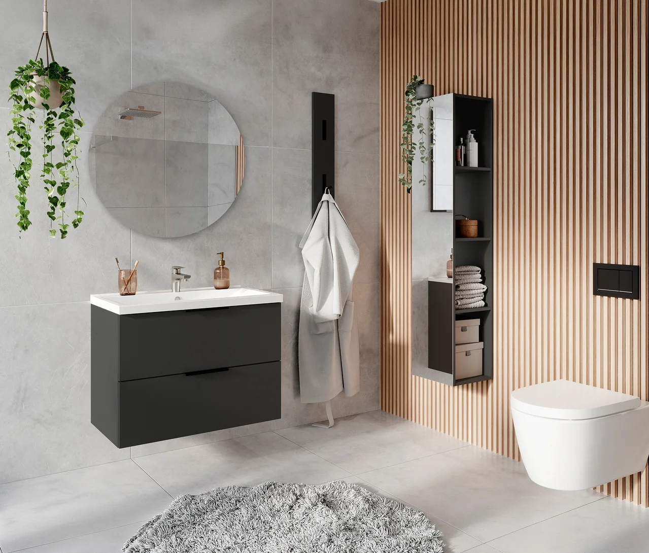 Modernes Badezimmer mit grauen Fliesenwänden und Holzlamellenverkleidung. Links ein dunkelgrauer Waschtisch "Crandon" inkl Becken, groß mit weißem Waschbecken unter einem runden Spiegel. Ein weißer Bademantel hängt an einem schwarzen Wandhaken. Rechts ein hoher schwarzer Schrank neben einer weißen wandhängenden Toilette. Ein grauer Badteppich liegt auf dem Boden.