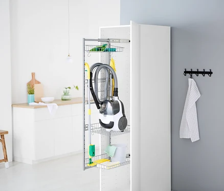 Ein Staubsauger und Reinigungsmittel sind in einem offenen, weißen Schrank verstaut.