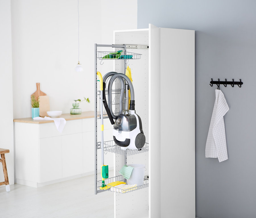 Ein Staubsauger und Reinigungsmittel sind in einem offenen, weißen Schrank verstaut.