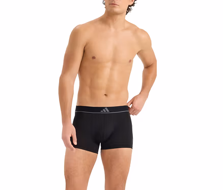 Oben ohne Mann in schwarzen Boxershorts mit grauem Bund und dreistreifigem Logo. Seine rechte Hand liegt am Bund.