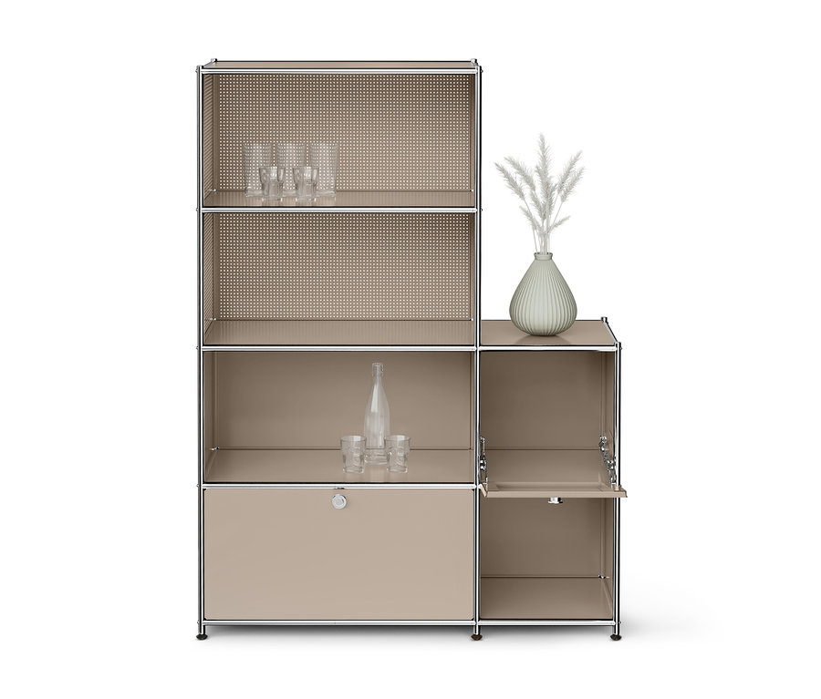 Ein beiges modulares Regal mit Chromrahmen. Die oberen linken Fächer haben perforierte Rückwände, das oberste Fach enthält klare Gläser. Das mittlere linke Fach enthält eine klare Flasche und zwei Gläser. Unten links befindet sich ein geschlossener Schrank. Das obere rechte Fach hat eine hellgrüne Vase mit weißen Zierpflanzen. Unten rechts ist ein offener Schrank mit einer Klapptür.