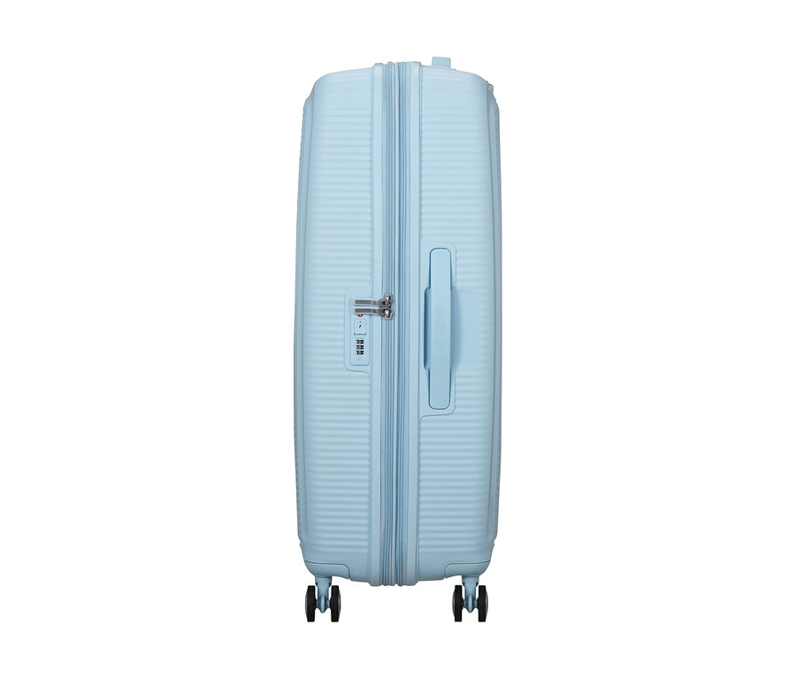 Pastellblauer American Tourister Soundbox Spinner Hartschalenkoffer mit gerippter Oberfläche, Zahlenschloss, ausziehbarem Griff und vier Rollen.