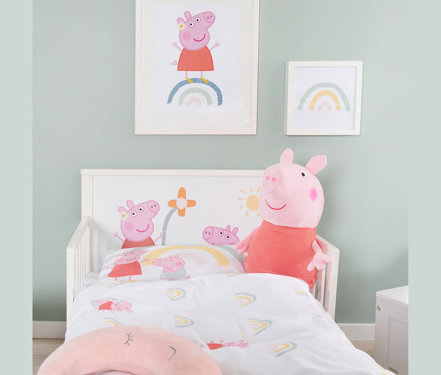 Ein Kinderzimmer mit einem Bett, das mit Peppa Wutz-Bettwäsche bezogen ist, einem Peppa Wutz-Plüschtier und zwei gerahmten Bildern an der Wand.