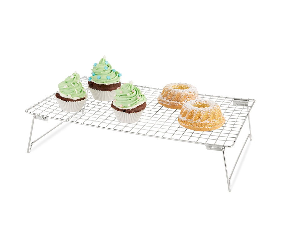 Drei Muffins mit grüner Dekoration und zwei Gugelhupfe mit Puderzucker auf einem 3-stöckigen Kühlgitter.