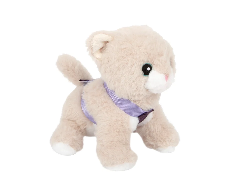 small foot Plüschkatze in Hellbeige mit weißen Pfoten, rosa Nase und schwarzen Augen, die ein lila Geschirr trägt und nach rechts blickt.
