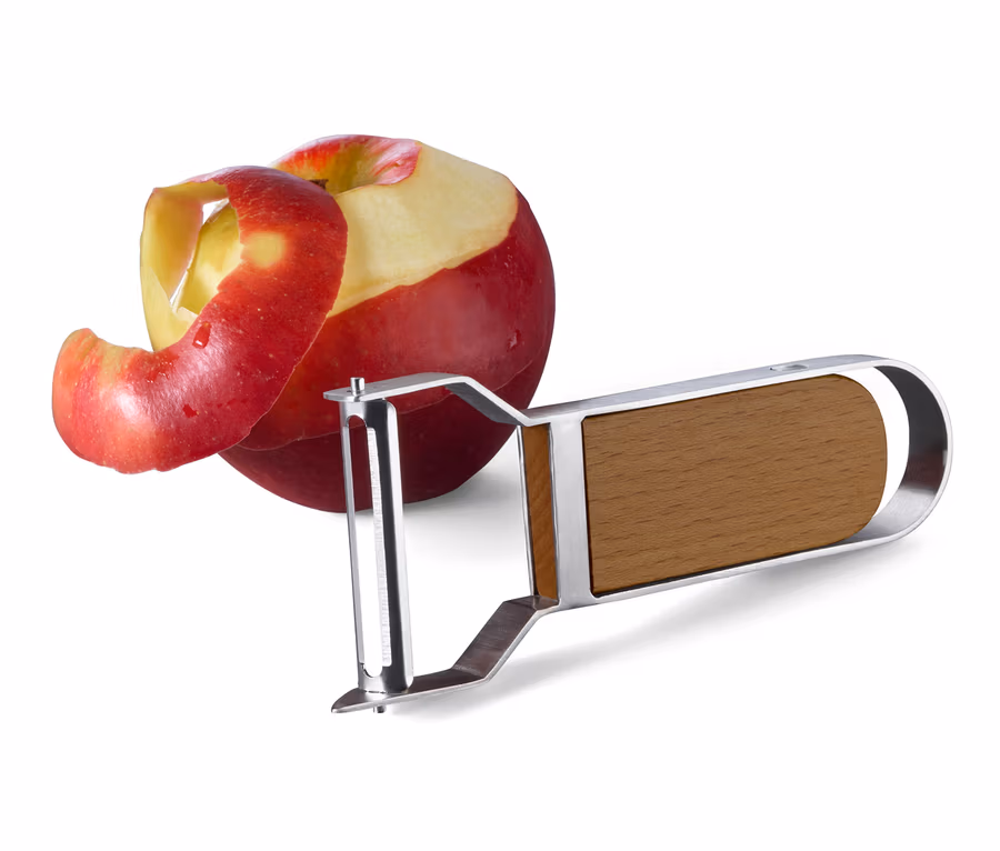 Ein roter Apfel mit Schale neben einem Universalschäler.