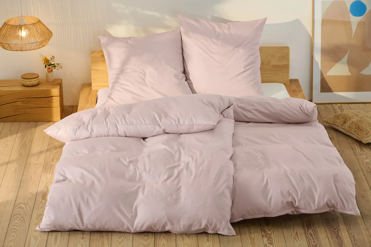 Rosafarbene Baumwollsatin-Bettwäsche in Normalgröße und Übergröße auf einem Bett.