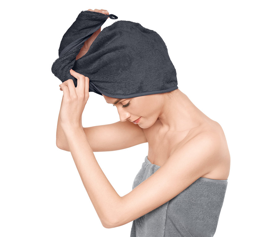 Frau setzt ein graues Turban-Handtuch auf.
