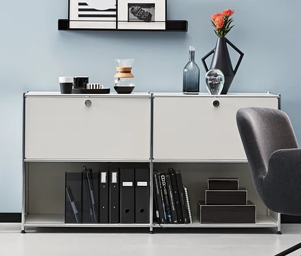 Ein Zimmer mit einem anthrazitfarbenen Schreibtischstuhl und Metall-Sideboards. Ein anthrazitfarbenes und zwei weiße Metall-Sideboards CN3 mit 2 versetzbaren Klappenfächern.