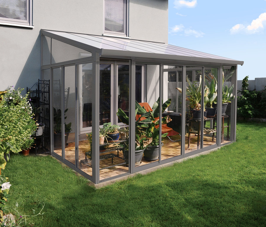 Ein anthrazitfarbener Wintergarten »San Remo« steht auf einer Rasenfläche neben einem Haus.