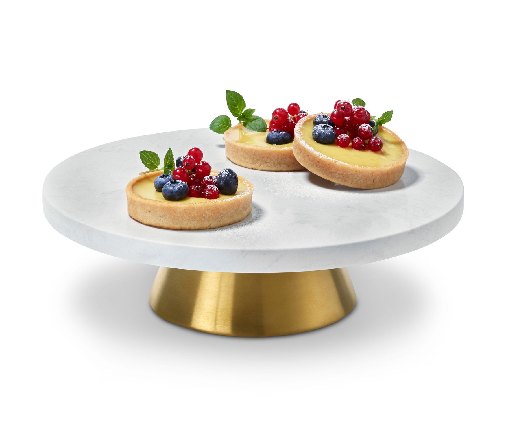 Drei Törtchen mit Früchten auf einer Etagere und Servierplatte.