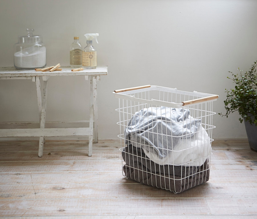 Ein weißer YAMAZAKI Wäschekorb »TOSCA«, Gr. L steht auf einem Holzboden.