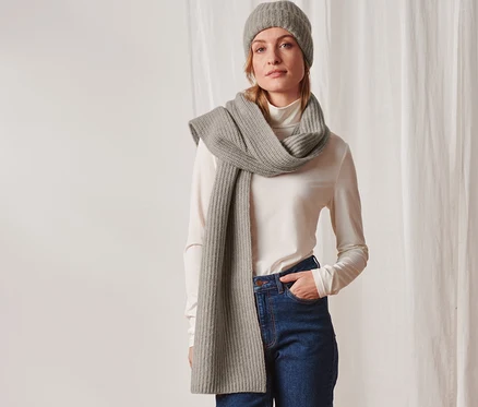 Frau posiert mit Strickschal in Taupe und Mütze.
