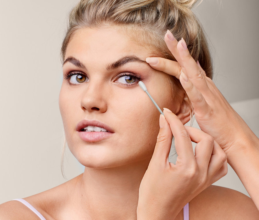 Frau entfernt Augen-Make-up mit Reinigungsstäbchen.