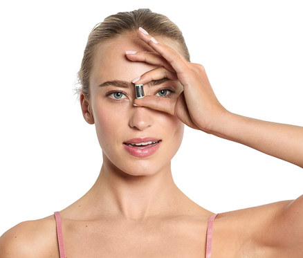 Frau hält Mini-Gesichtsepilierer vor ihrem Auge.