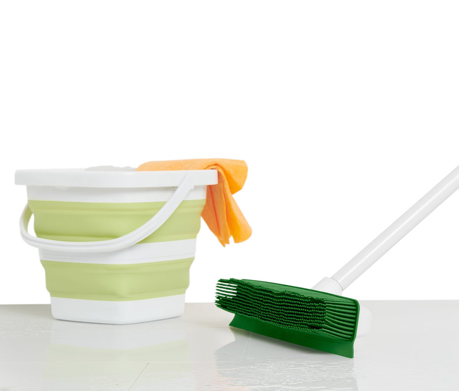 Ein grüner Universal-Reinigungsbesen mit weißem Stiel steht neben einem zusammenklappbaren Eimer mit einem orangefarbenen Tuch.