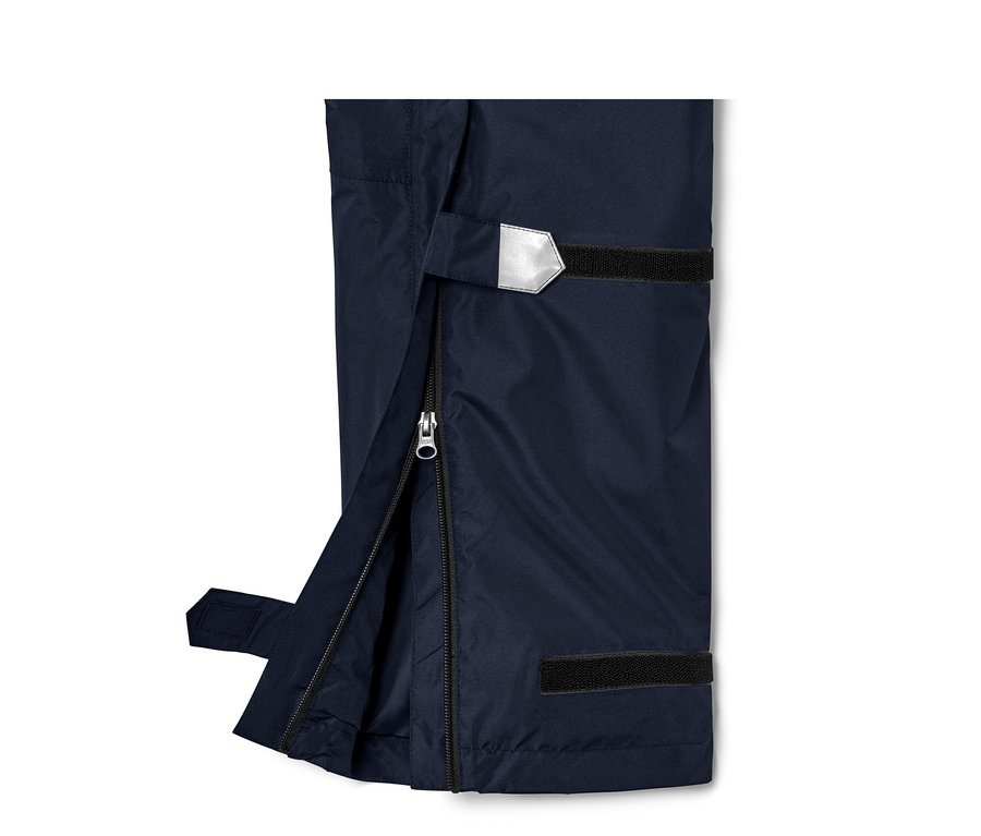 Detail einer Unisex-High-Tech-Regenhose mit geöffnetem Reißverschluss und reflektierendem Detail.