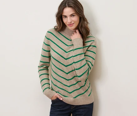 Frau posiert in einem creme-farbenen, gestreiften Strickpullover mit Stehkragen.