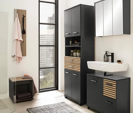 Badezimmer mit anthrazitfarbenem Katta Spiegelschrank, Waschbeckenunterschrank mit 1 Tür und 2 Schubladen, Hochschrank und Badhocker.