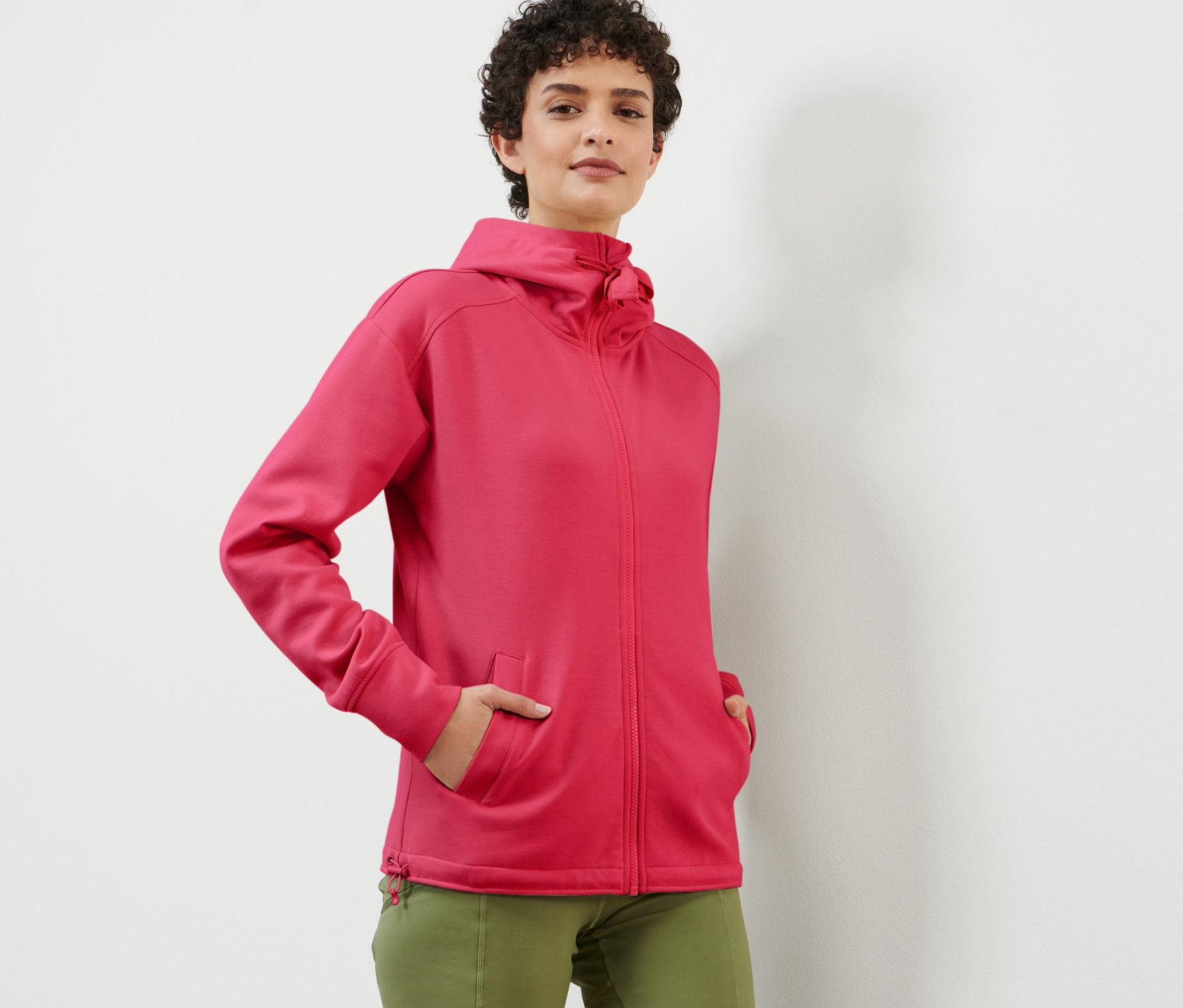 Frau posiert in beerefarbener Kapuzen-Sweatjacke.