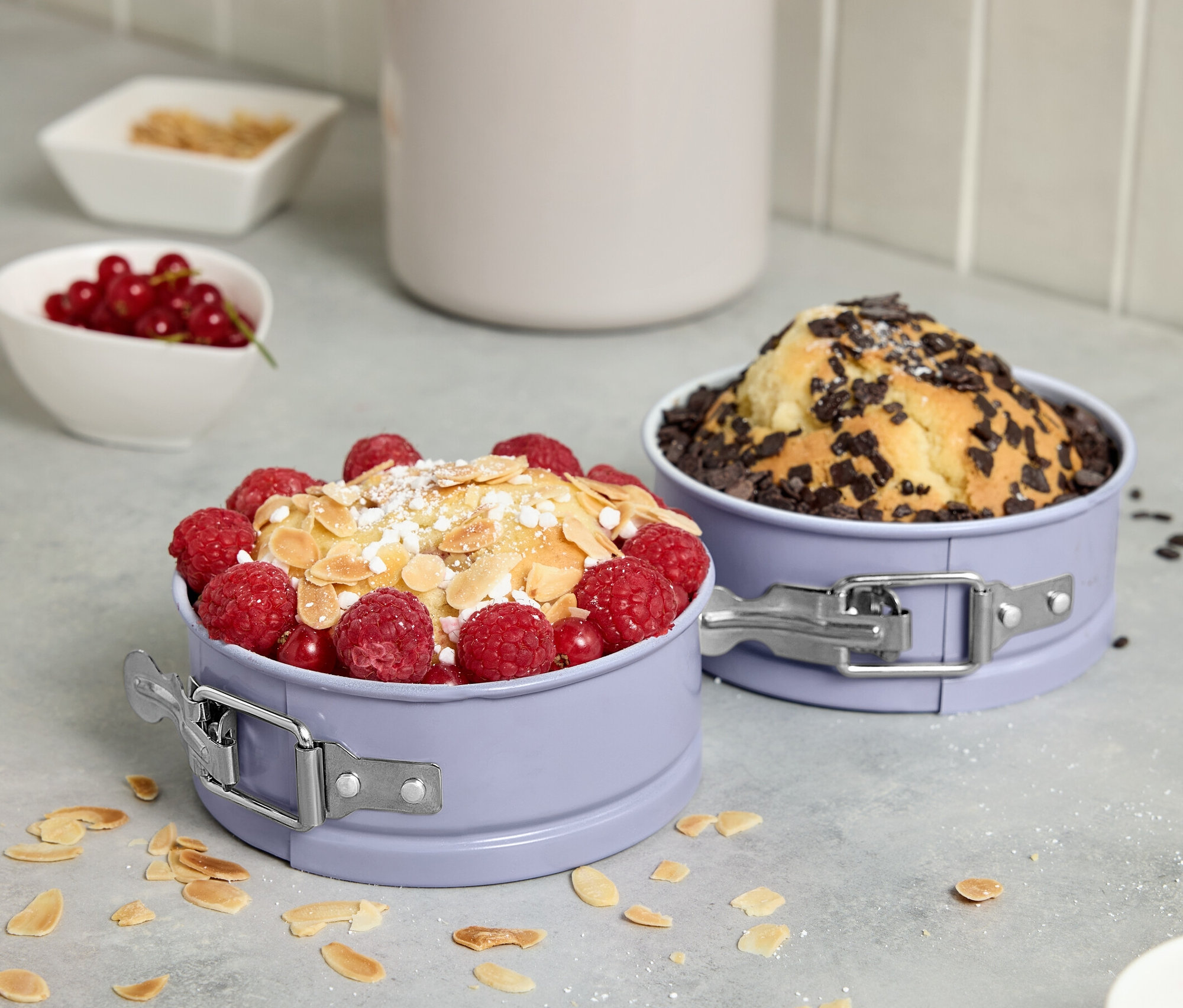 Zwei Mini-Springformen mit Kuchen, garniert mit Früchten und Schokolade.