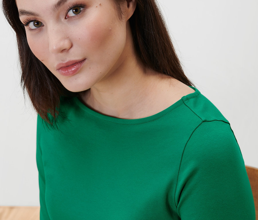 Porträt einer Frau in einem grünen Shirt mit 3/4-Arm.