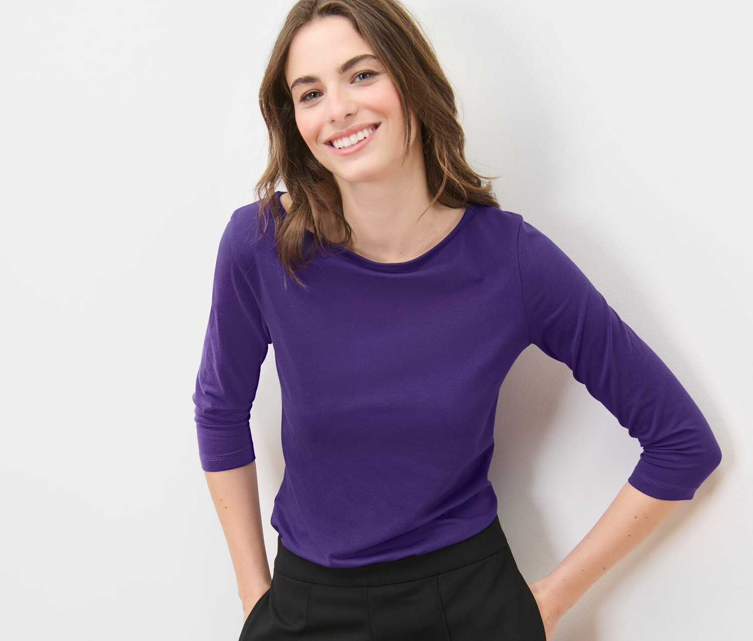 Frau posiert in lila Shirt mit 3/4-Arm.