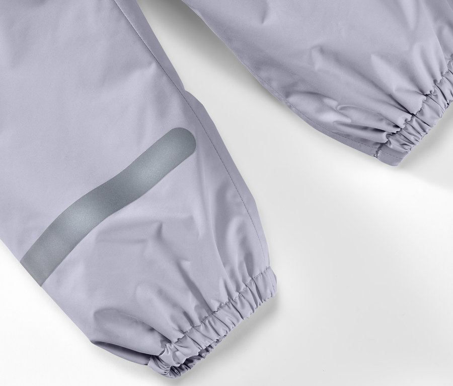 Detail einer Kinder-Regenhose mit silbernem Reflexstreifen am Bein und elastischem Saum am Knöchel.